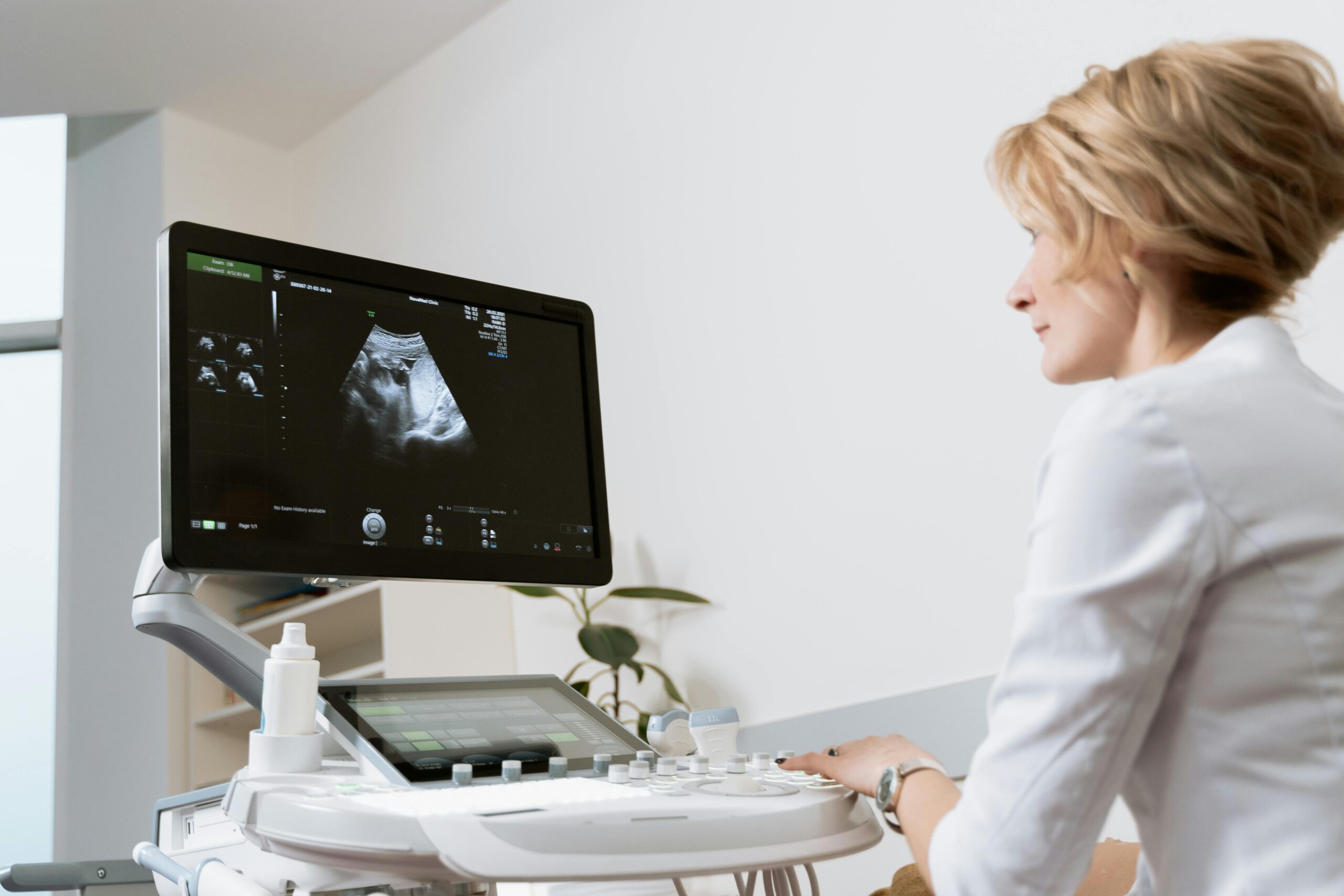 Female doctor using ultrasound scanner in modern medical clinic.