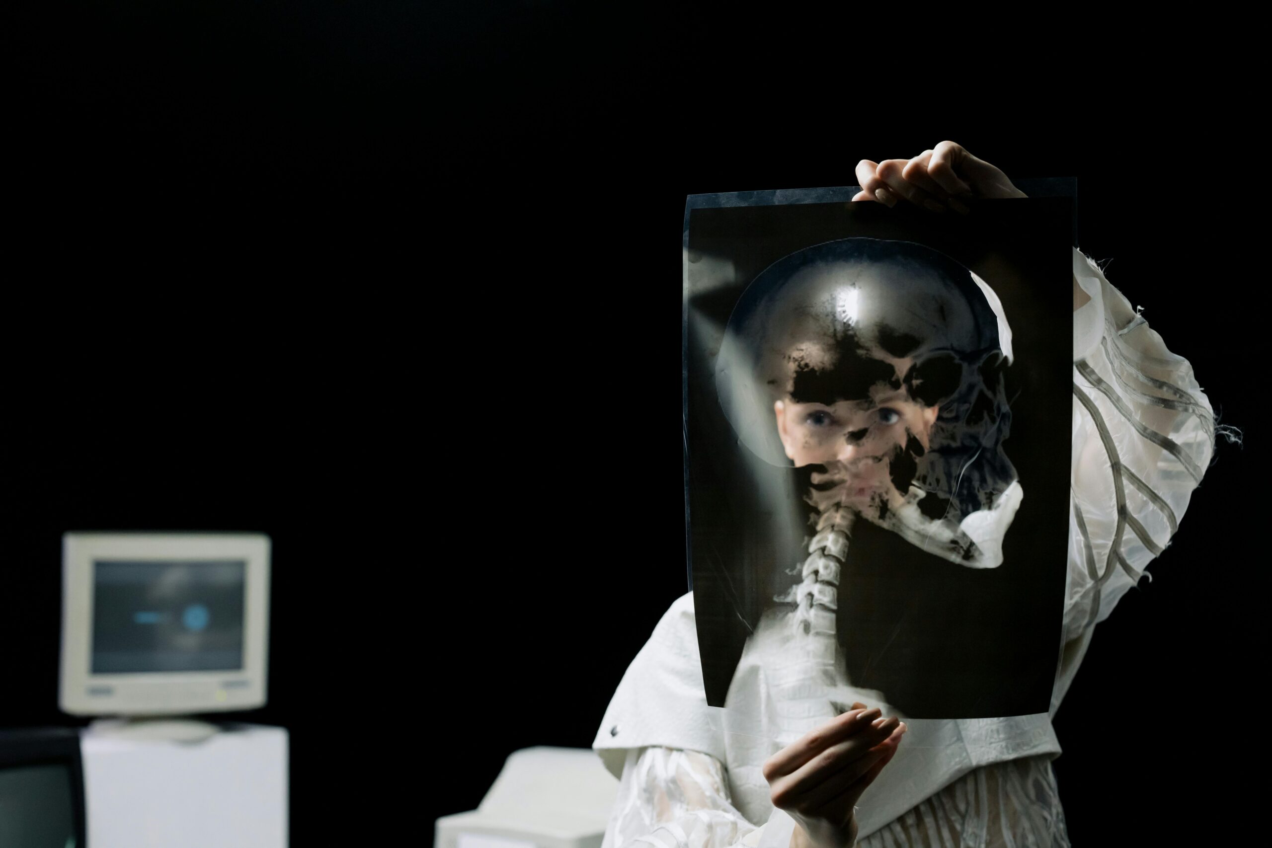 A woman holds a skull X-ray in a dark laboratory, with scientific equipment in the background.